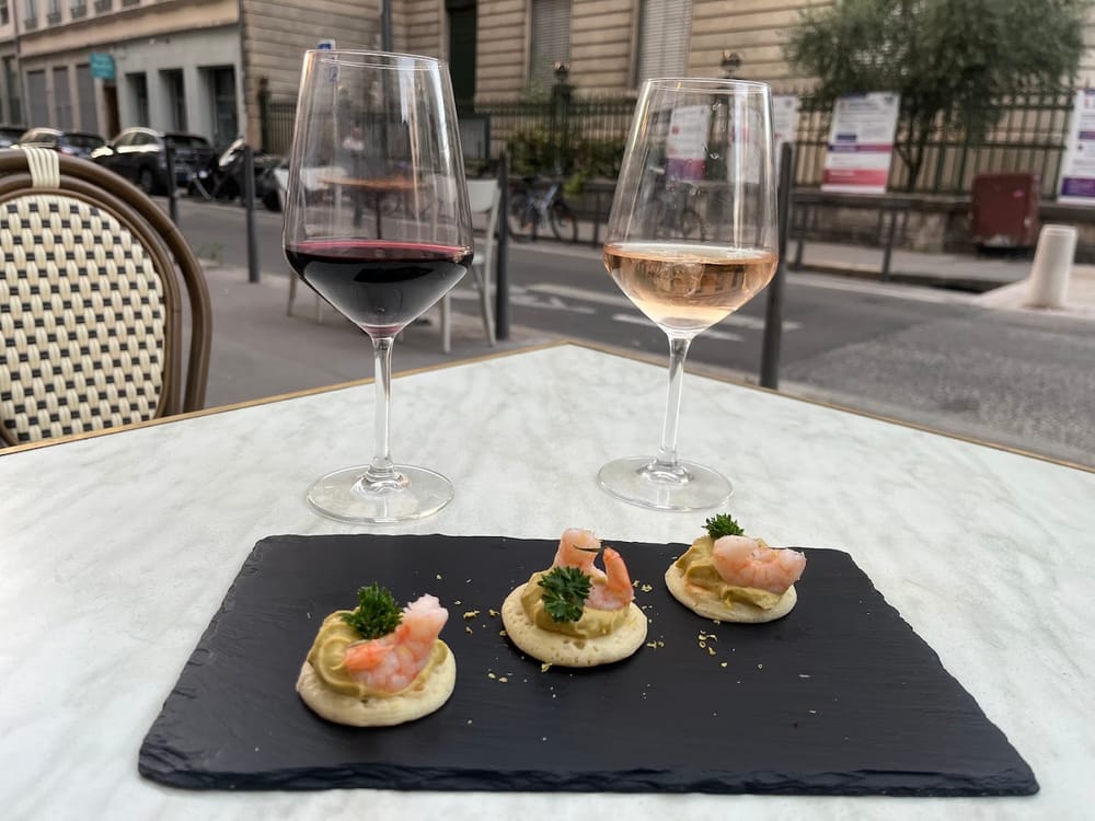 Un verre de vin rouge, un verre de rosé et des canapés aux crevettes sur une ardoise